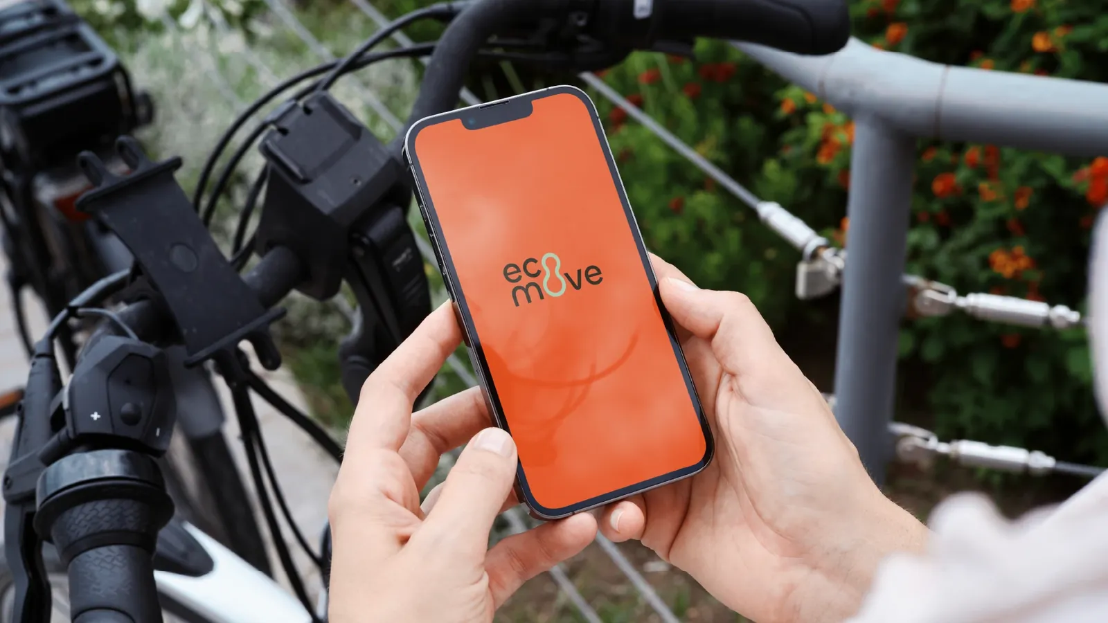 Celular com o app da Ecomove em laranja, preso ao guidão de uma bicicleta elétrica